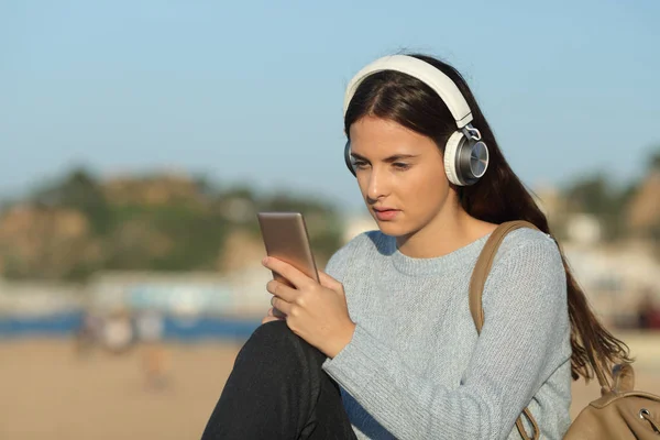 Chica seria escuchando música comprobando el teléfono inteligente — Foto de Stock