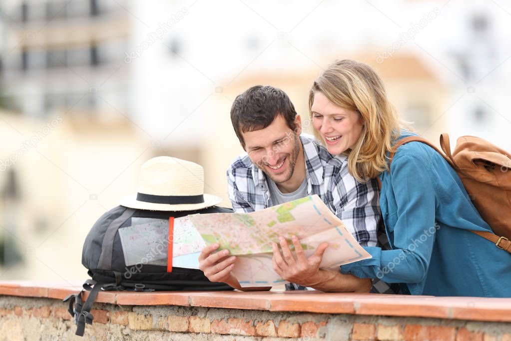 Happy couple of tourists checking map on vacation