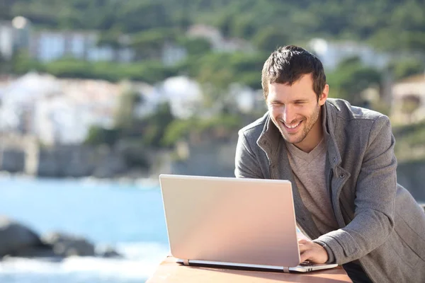 Uomo felice utilizzando un computer portatile in un balcone in inverno — Foto Stock