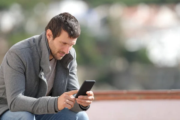 Ciddi bir yetişkin adam kışın açık havada akıllı telefon kullanıyor. — Stok fotoğraf