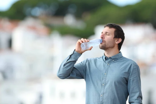 Взрослый мужчина пьет бутилированную воду на открытом воздухе — стоковое фото