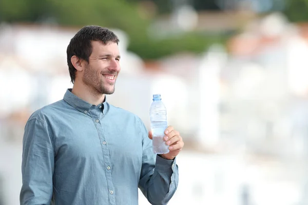 Dışarıda elinde bir şişe su tutan mutlu yetişkin bir adam. — Stok fotoğraf