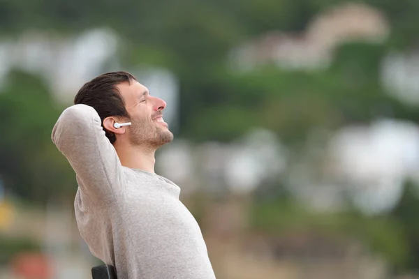 Glücklicher Mann, der Musik mit drahtlosen Ohrhörern hört — Stockfoto