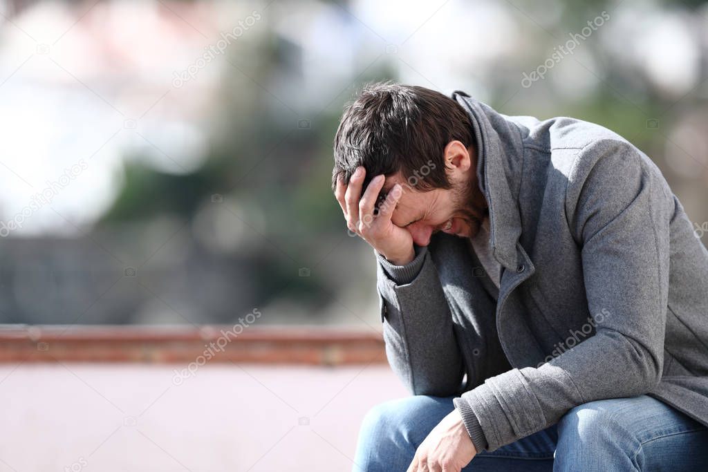 Worried man complaining sitting on a bench in winter