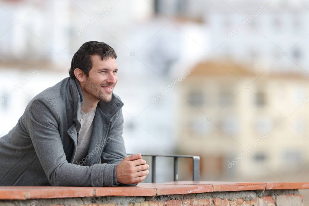 Happy man in winter contemplating views in a balcony