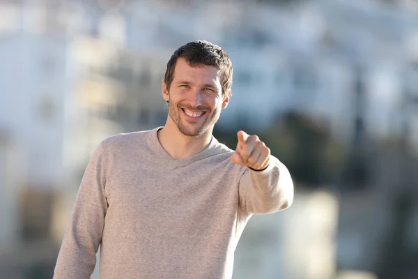 Happy adult man pointing at camera in a rural town