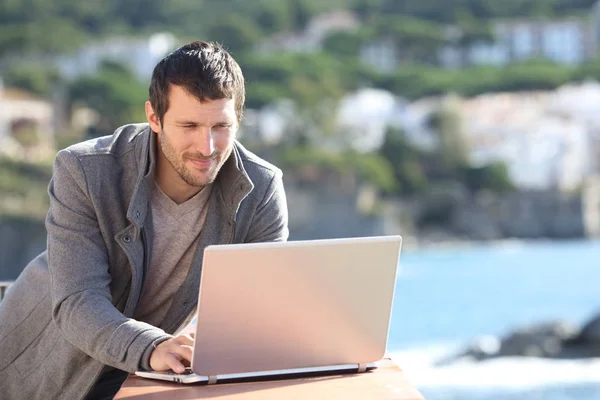 Homem sério usando um laptop em uma varanda no inverno — Fotografia de Stock