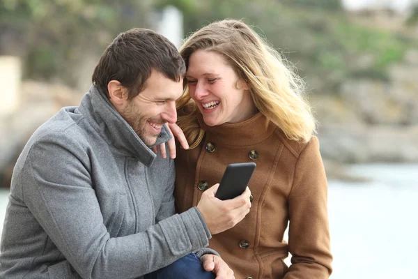 Glada par skrattar talar om telefoninnehåll — Stockfoto