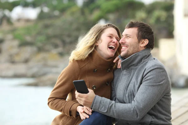 Un par de adultos riendo en voz alta sobre el contenido del teléfono —  Fotos de Stock