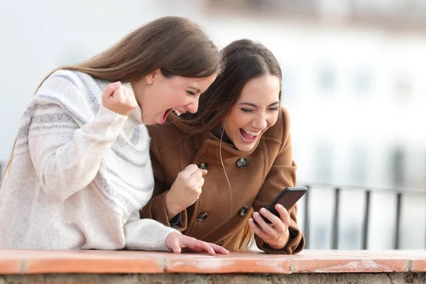 Mulheres excitadas verificando notícias telefônicas no inverno — Fotografia de Stock