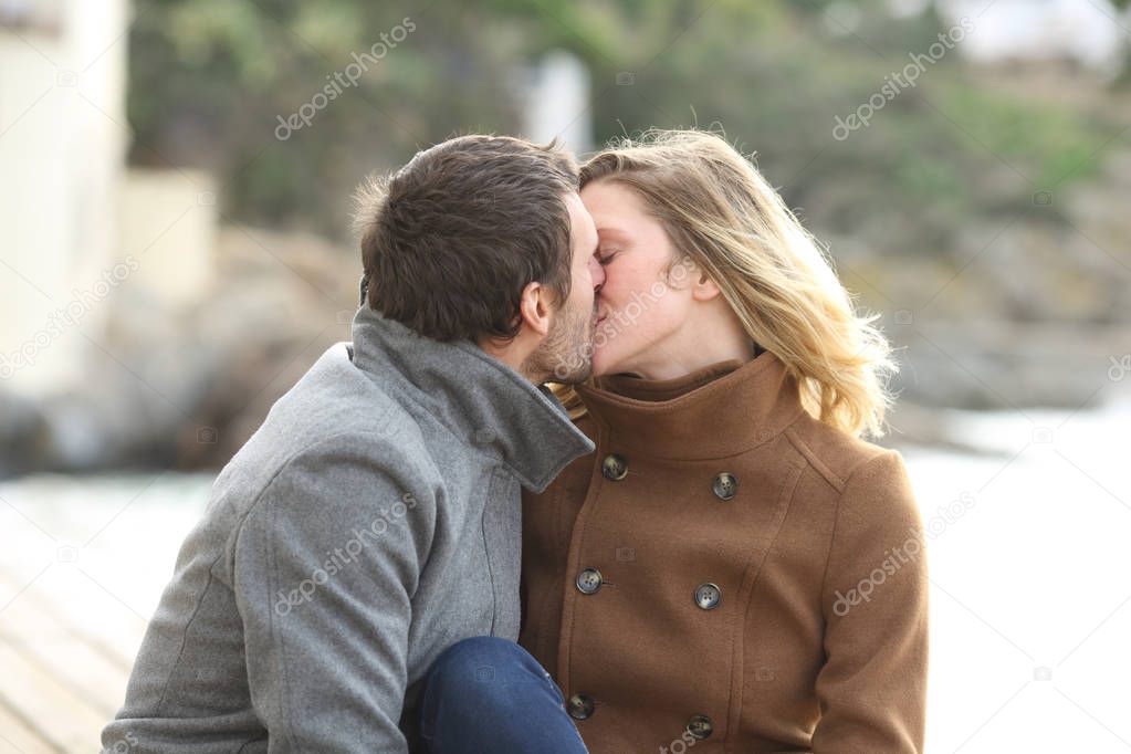 Adult couple in love kissing on the beach in winter