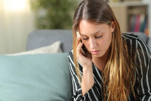 Poważna kobieta rozmawiająca przez telefon na kanapie w domu — Zdjęcie stockowe