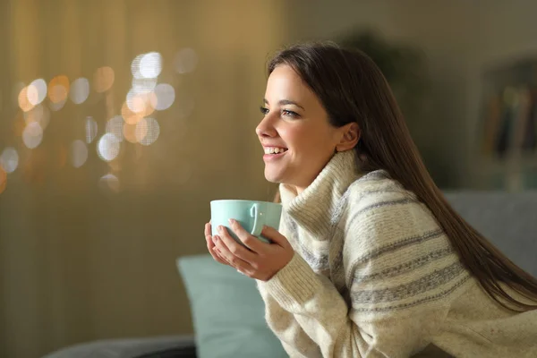 Счастливая женщина держит чашку кофе зимой дома — стоковое фото