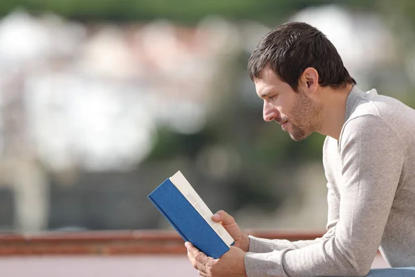 Расслабленный взрослый мужчина читает книгу на открытом воздухе — стоковое фото