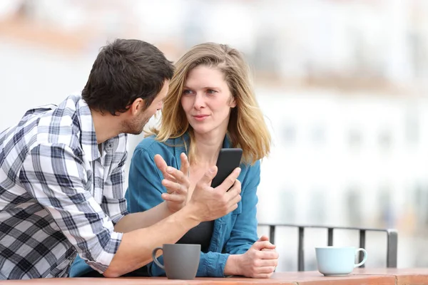 Paar praten over telefooninhoud op een balkon — Stockfoto