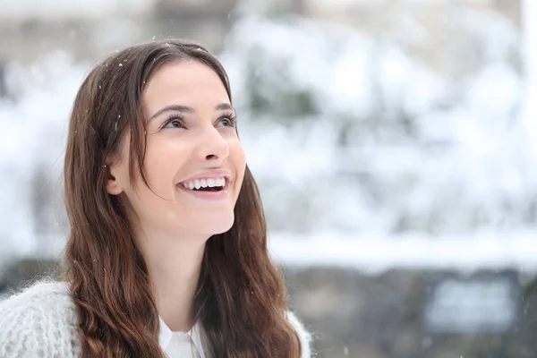 Откровенная счастливая девушка смотрит на снег, падающий зимой — стоковое фото
