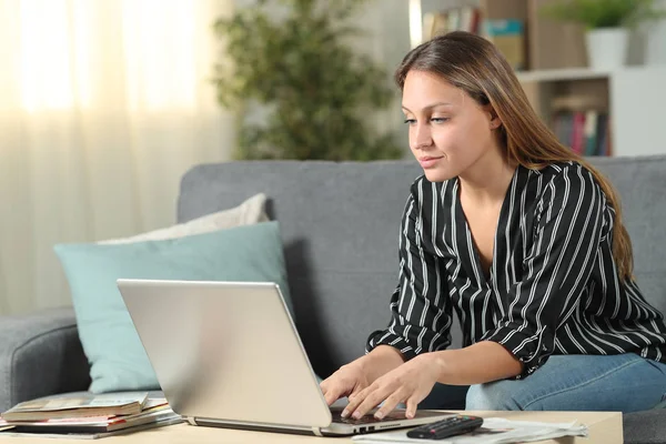 Mujer seria escribiendo en el ordenador portátil sentado en un sofá — Foto de Stock