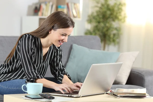 坐在家里，坐在笔记本电脑上写作的快乐女人 — 图库照片