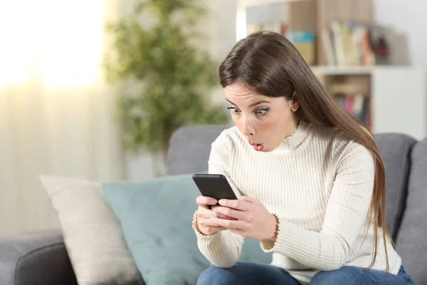 Terkejut wanita memeriksa isi telepon pintar di rumah — Stok Foto