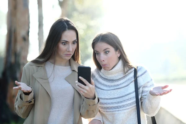 Donne perplesse che controllano il contenuto del telefono cellulare — Foto Stock