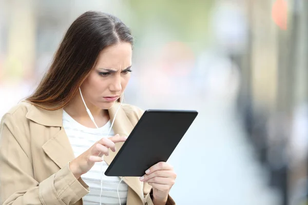 Chica frustrada con auriculares comprobar los medios de comunicación en la tableta — Foto de Stock