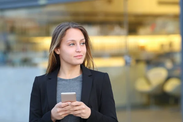 Affärskvinna håller telefonen tittar på sidan på gatan — Stockfoto