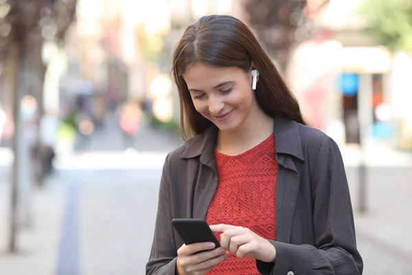 Fille heureuse portant des écouteurs écouter de la musique sur le téléphone — Photo