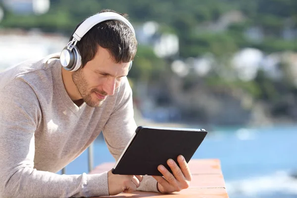 Homem adulto com fones de ouvido verificando conteúdo tablet — Fotografia de Stock