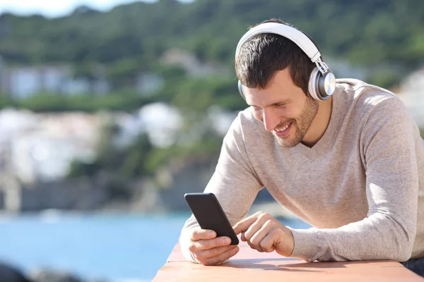 Kulaklıklı mutlu yetişkin adam telefon içeriğini kontrol ediyor. — Stok fotoğraf