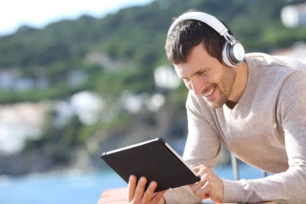 Happy adult man with headphones checking tablet content — 스톡 사진