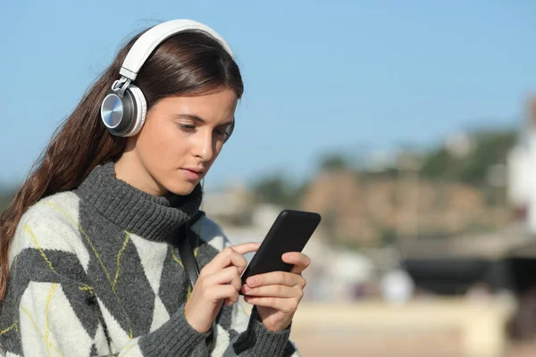 電話で音楽を聴くヘッドフォンを持つ深刻な女の子 — ストック写真