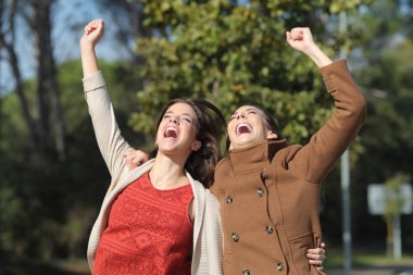 İki heyecanlı kadın birlikte atlayarak başarıyı kutluyor.