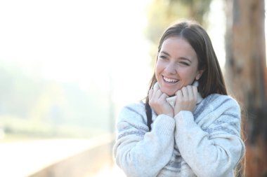 Mutlu kadın kışın sıcacık giyinerek yürüyor.