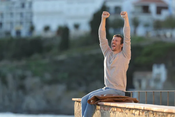 兴奋的男人举起双臂庆祝阳台上的成功 — 图库照片