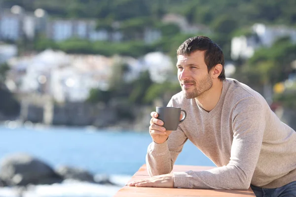 Allvarlig man dricker kaffe överväger utsikt på en balkong — Stockfoto