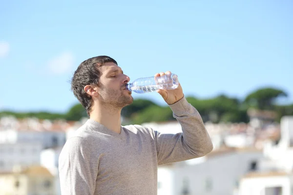 Perfil de um homem adulto bebendo água engarrafada em uma cidade — Fotografia de Stock