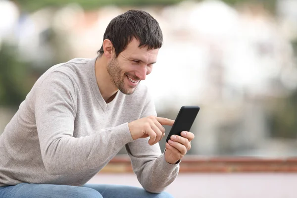 Hombre feliz en un banco usando teléfono móvil — Foto de Stock