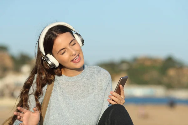 Счастливая девочка поет и слушает музыку на пляже — стоковое фото