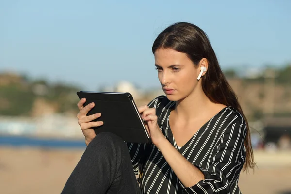 Aprendizaje electrónico serio de la mujer con una tableta y auriculares — Foto de Stock