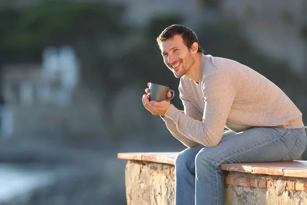 Hombre feliz sosteniendo taza de café contemplando vistas Fotos de stock libres de derechos