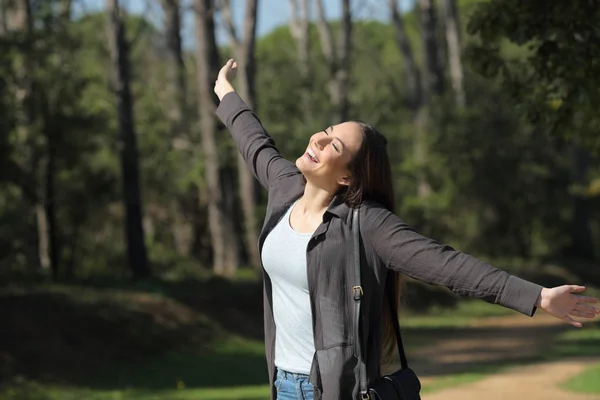 Щаслива жінка, яка святкує новий день, розтягує руки в парку — стокове фото