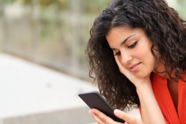 Düşünceli kadın akıllı telefondan mesaj okuyor.