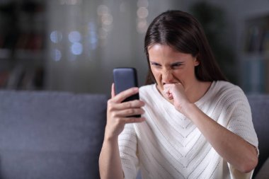 Sinirli kız gece telefon içeriğini kontrol ediyor.