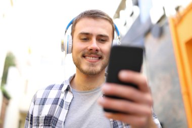 Sokakta yürürken müzik dinleyen mutlu adamın ön görüntüsü.
