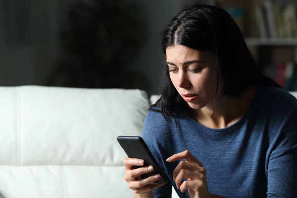 Занепокоєна жінка перевіряє текст мобільного телефону вночі — стокове фото