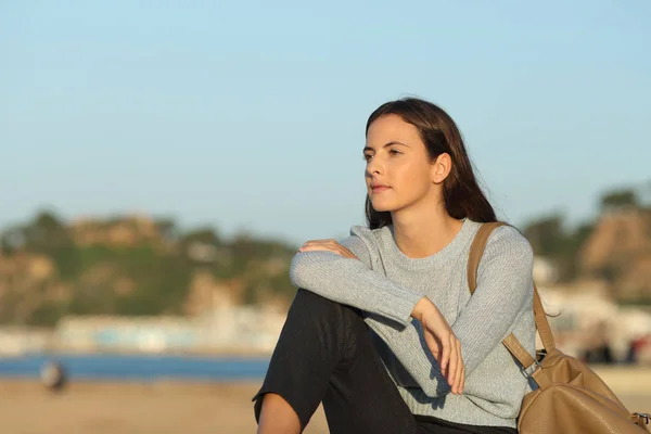 Sebevědomá žena dívá pryč sedí na pláži — Stock fotografie