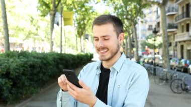 Cep telefonu kullanan şaşırmış bir adam inanılmaz içerikler buluyor ve kameraya bakıyor. 