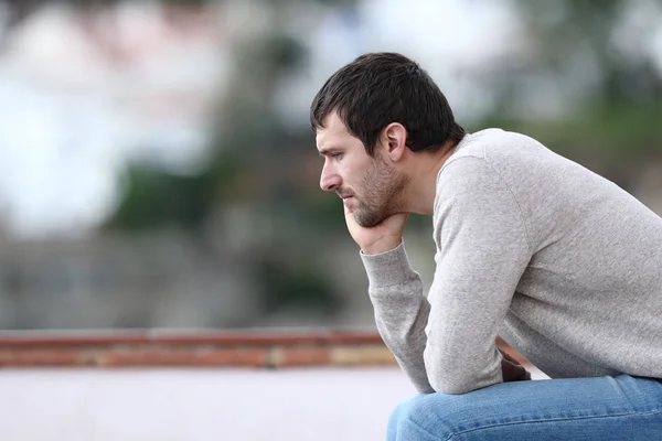 Pensive ustaraný muž sedí na lavičce — Stock fotografie