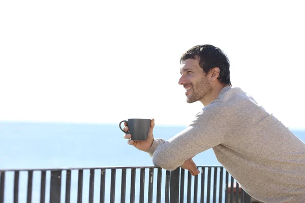 Hombre feliz sosteniendo la taza contemplando las vistas desde un balcón — Foto de Stock