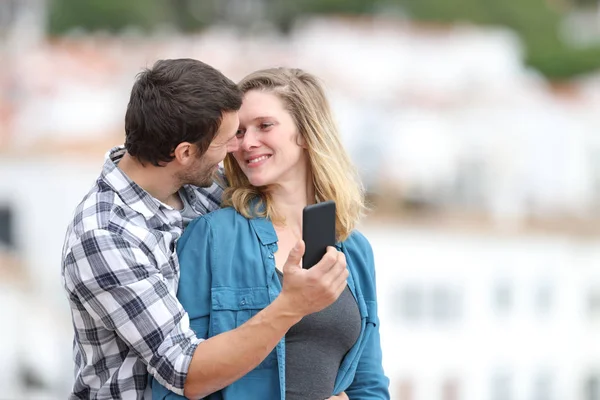 Casal feliz flertando segurando telefone inteligente — Fotografia de Stock